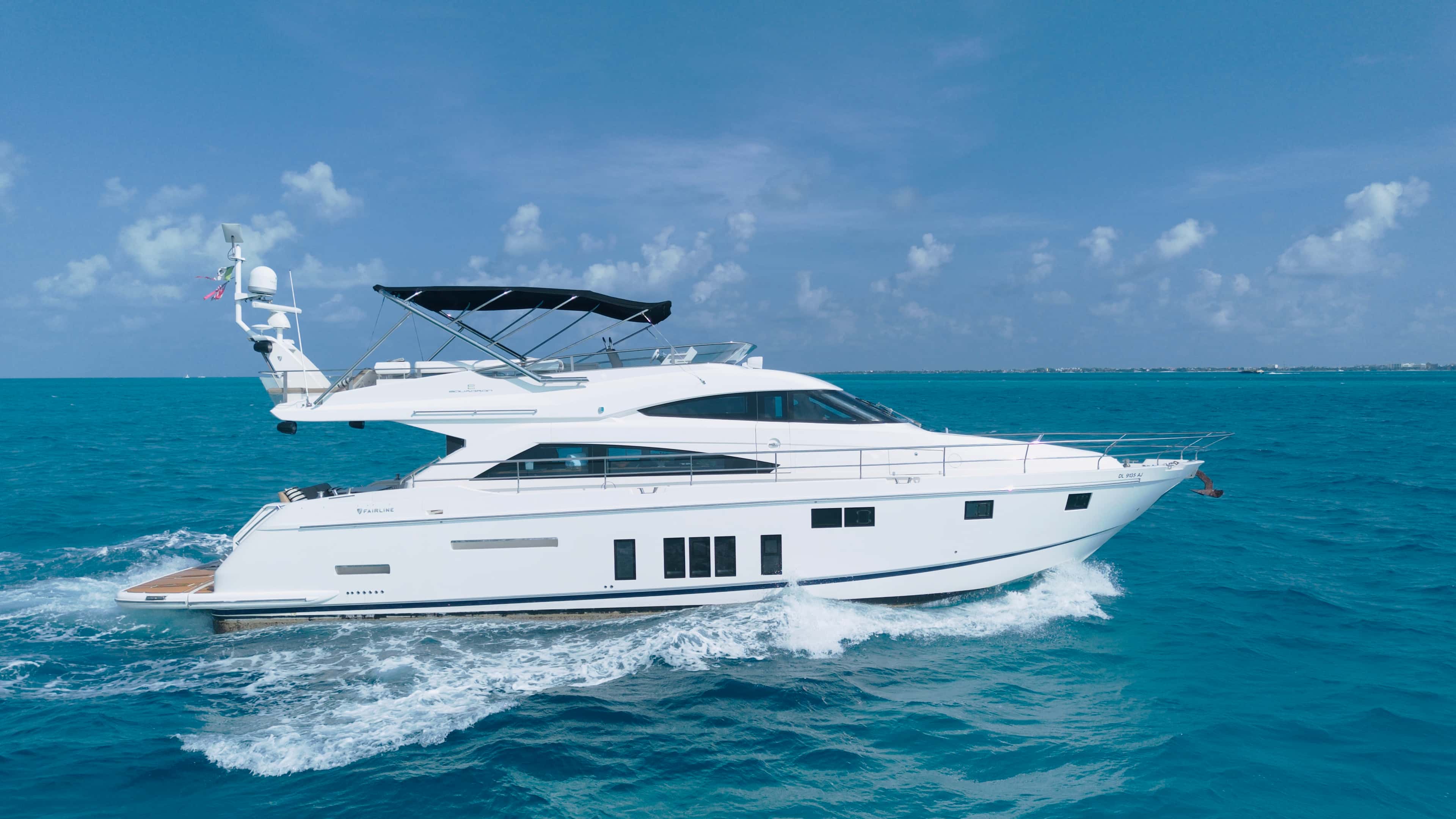 Addicted under way in full profile, white hull and flybridge over turquoise water