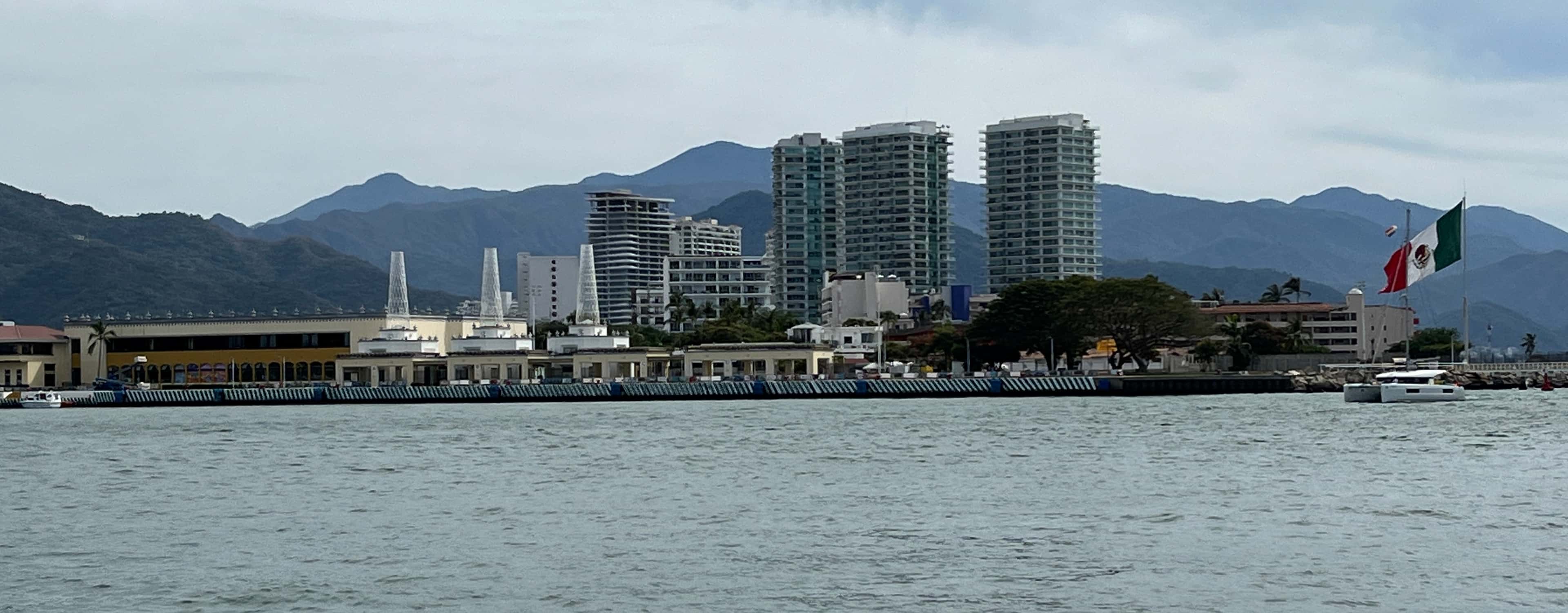 Marina Vallarta: the waterfront and breakwater seen from the water, with the large Mexican flag