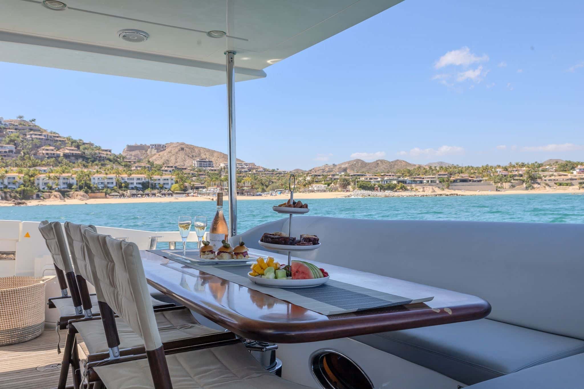 Lunch platters and fruit set on the aft deck table, the beach and hills behind