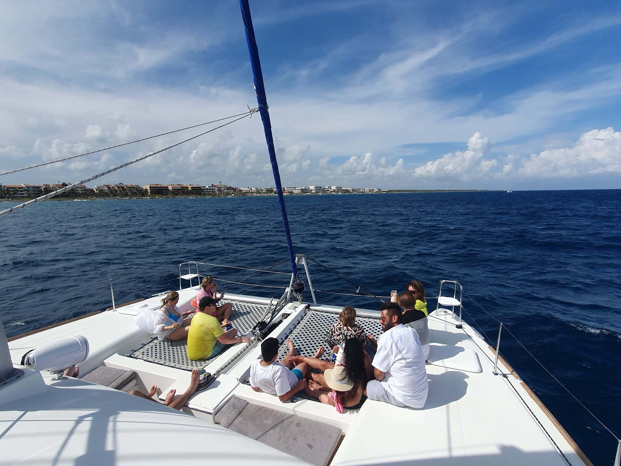 Guests on the foredeck seats as the catamaran heads out, the coast in the distance