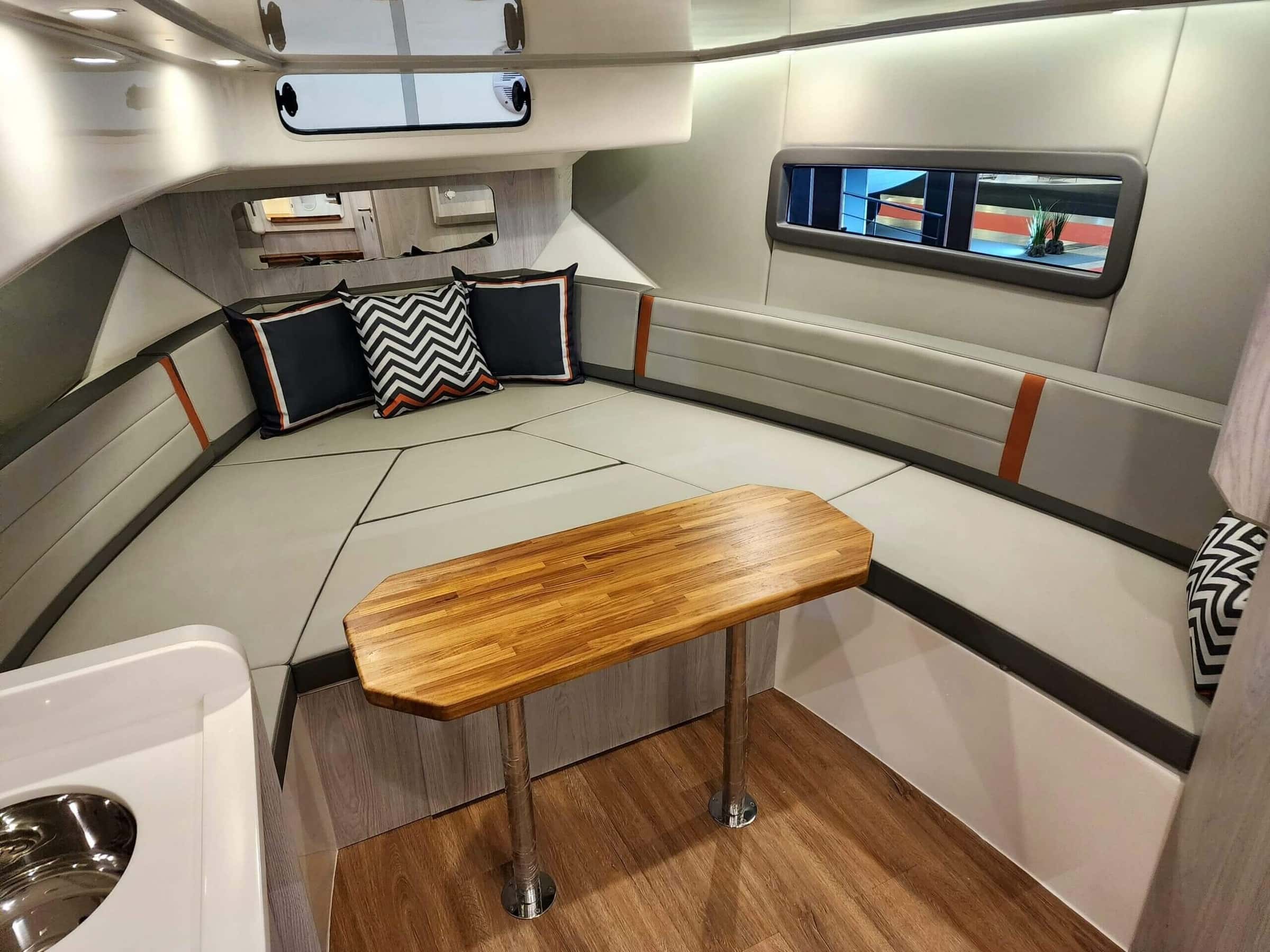 Cabin of another Flyer 38 HT: a grey U-shaped settee with cushions around a wood table in the bow