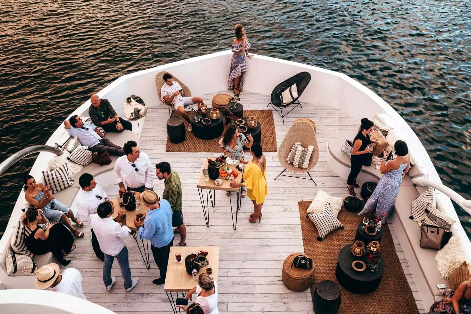 Guests at high tables and lounge chairs on the bow deck, seen from above