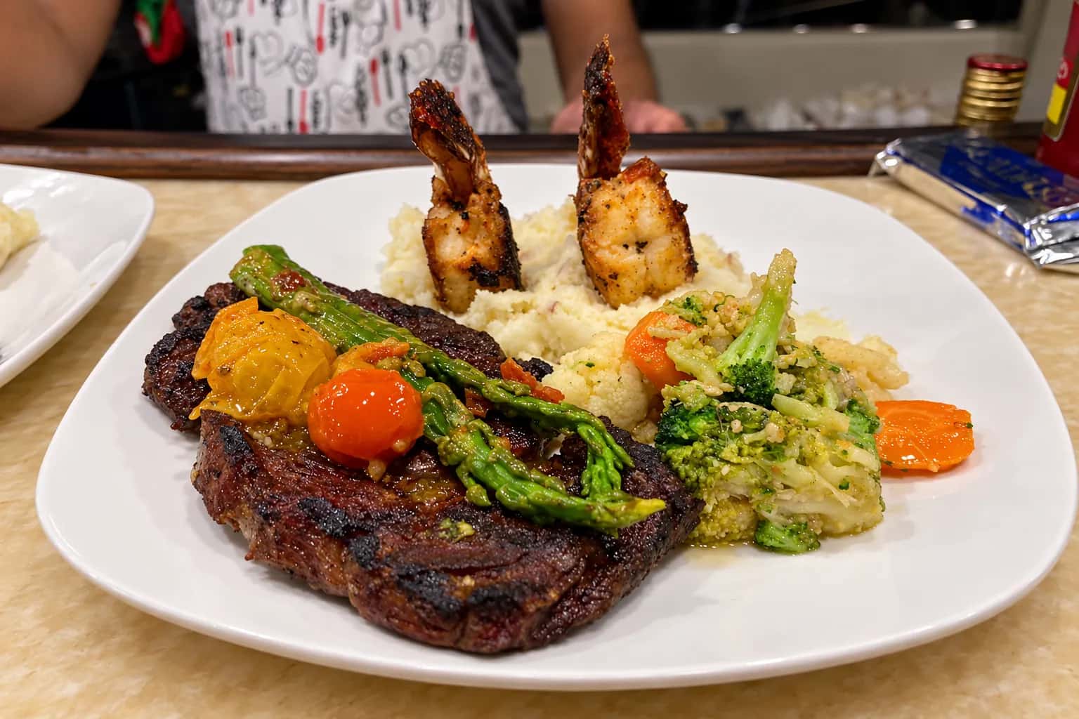 Grilled rib steak with two charred shrimp, mashed potatoes, asparagus and roasted vegetables
