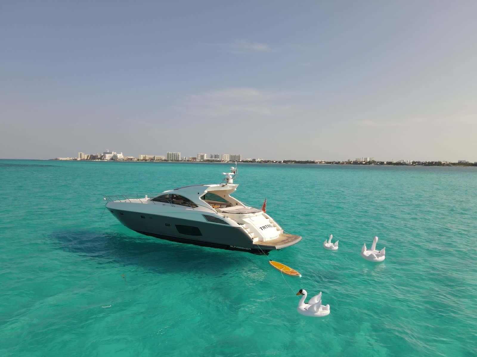 Tatabu at anchor off the Cancun hotel zone, with swan floats and a paddle board astern