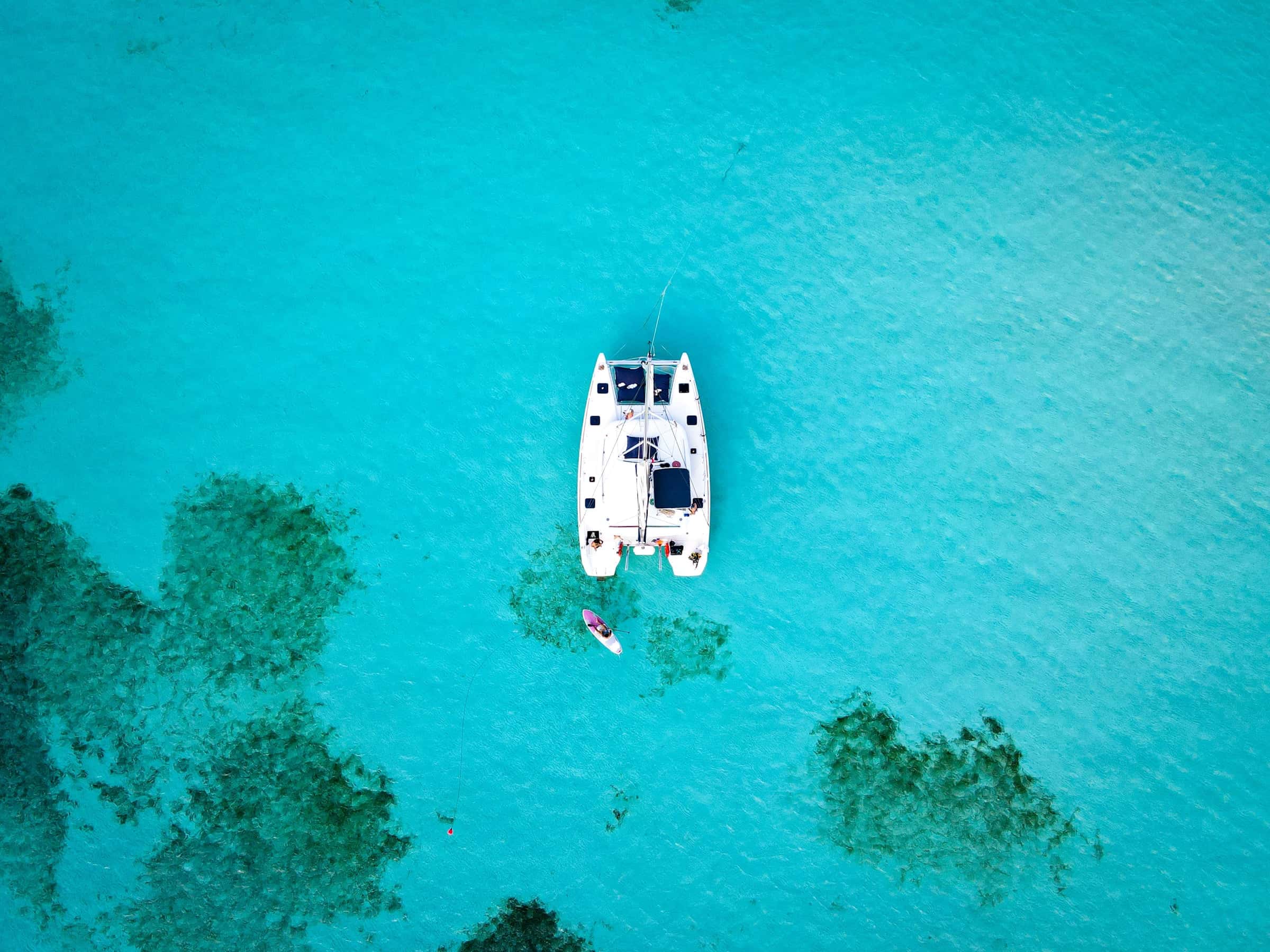 Catamaran from directly above, at anchor over pale sand and dark seagrass patches