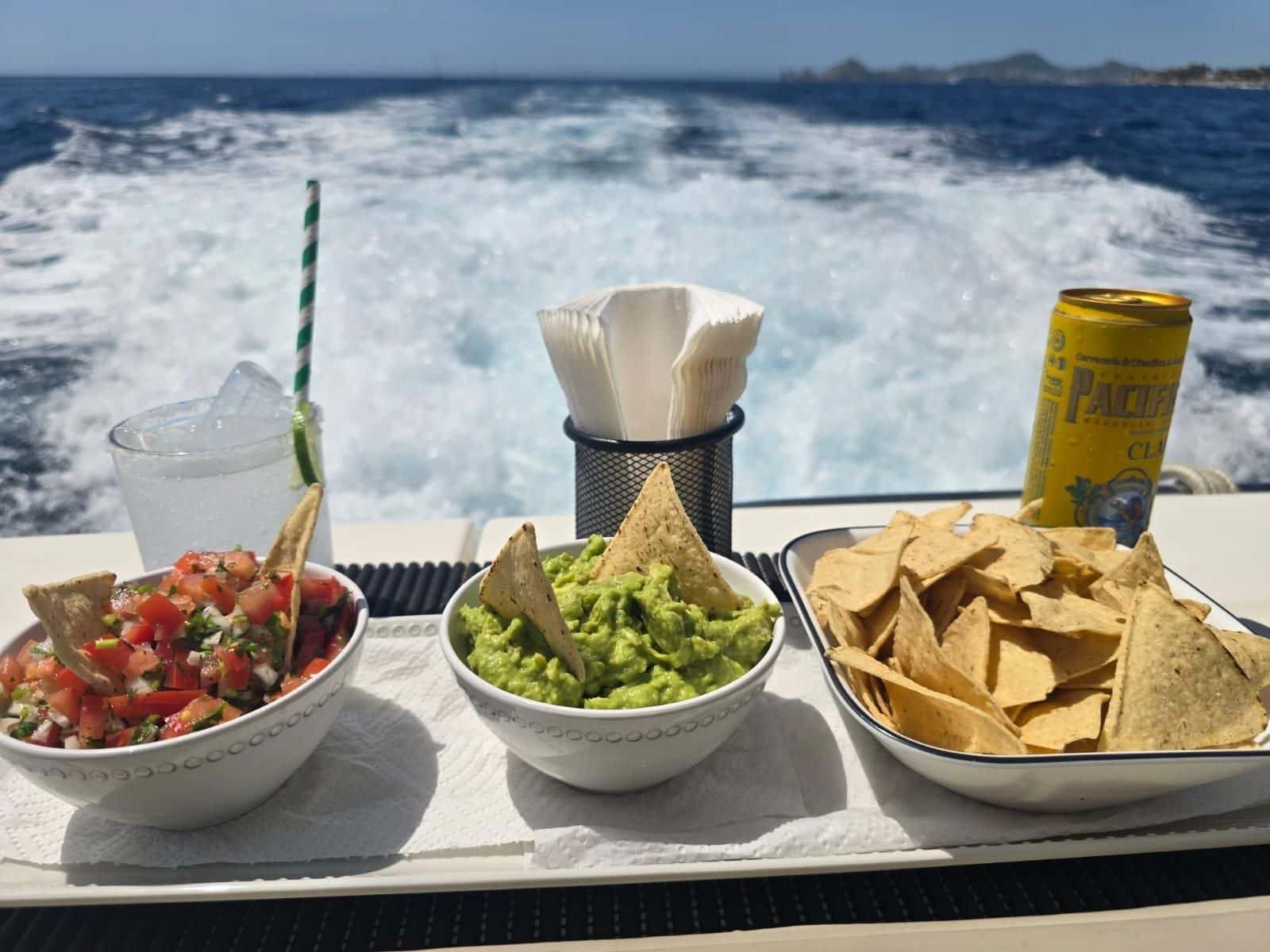 Bowls of pico de gallo, guacamole and tortilla chips on the stern rail, the wake behind