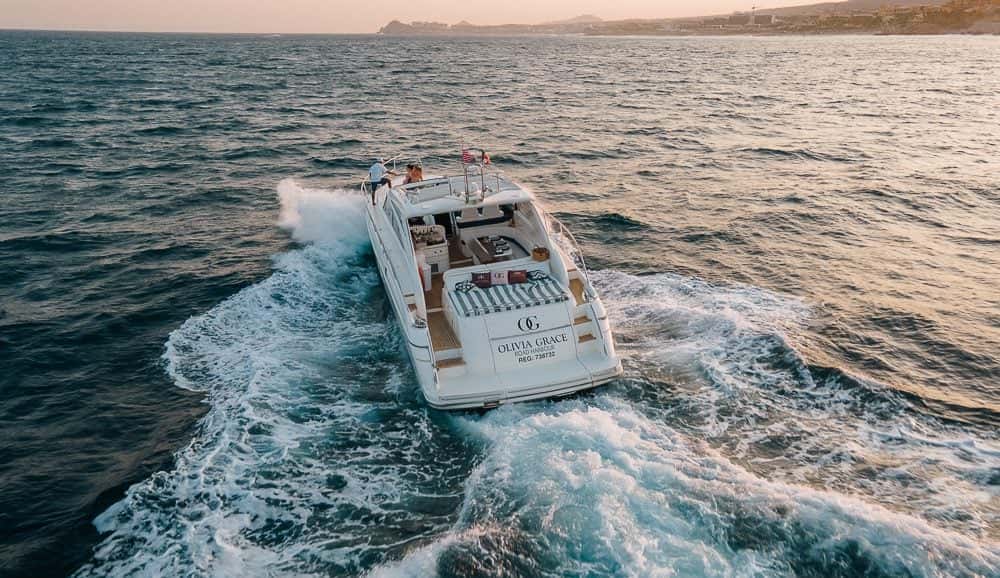 Aerial view from astern of the yacht cutting a white wake at sunset