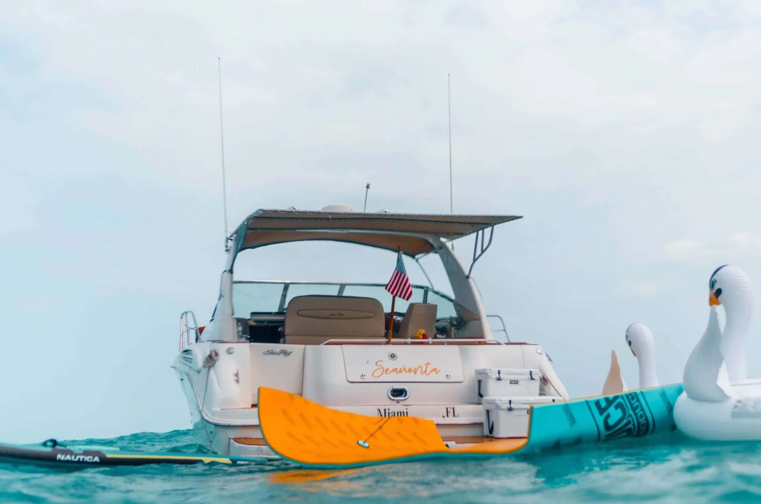 Stern of Seañorita at water level with the paddle board, floating mat and a swan float at the swim platform