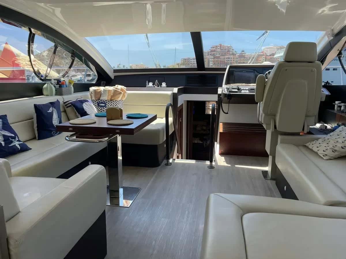 Saloon with cream sofas, a dinette table and the helm seat beside wide windows