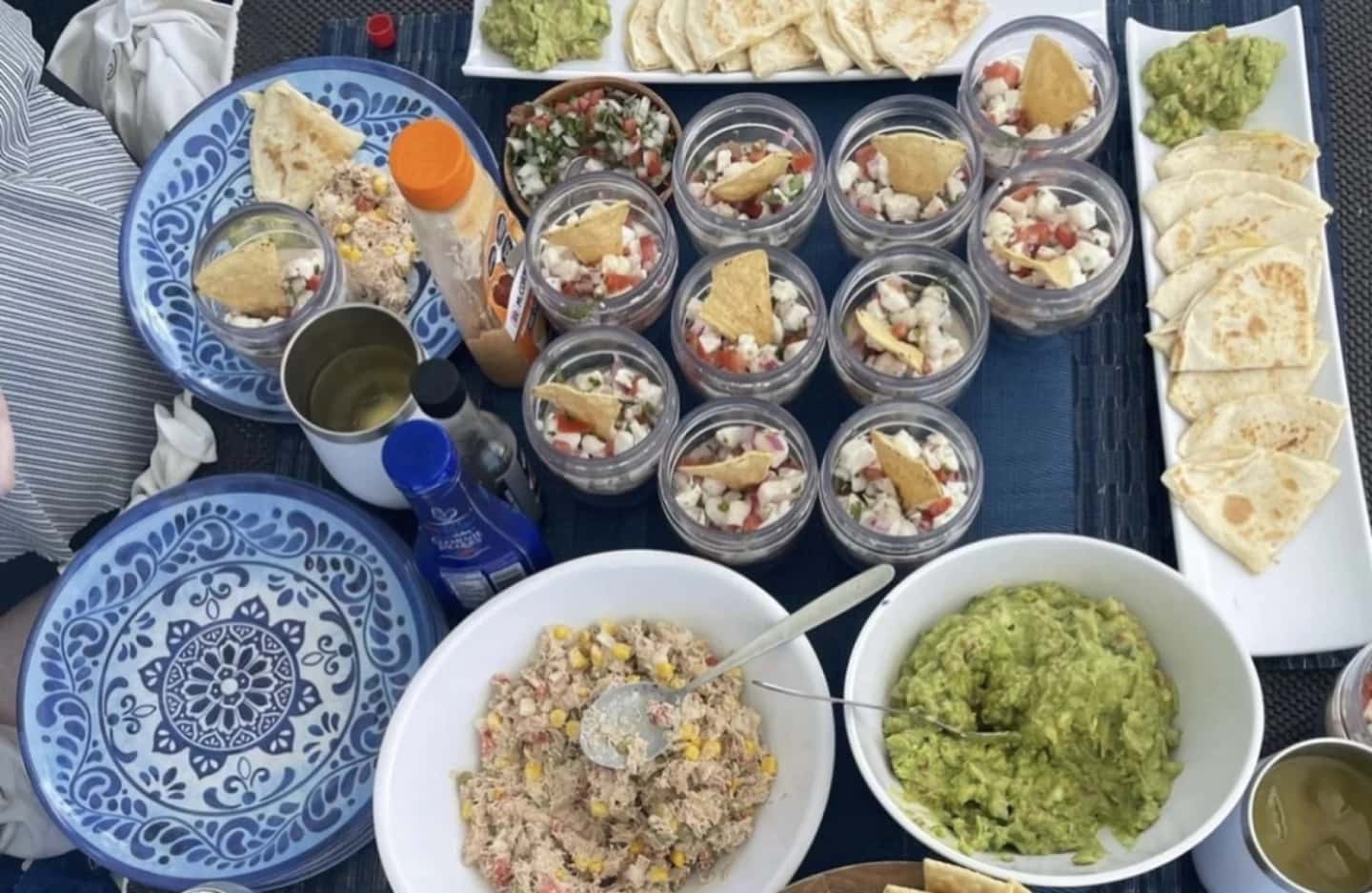 Lunch on the cockpit table seen from above, with ceviche in glass cups, quesadilla wedges, guacamole and a corn and tuna salad.