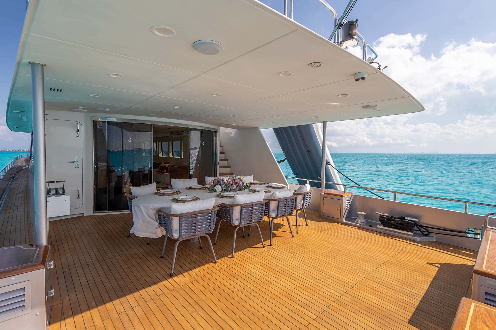 Aft deck dining table seen from the side with the salon doors open