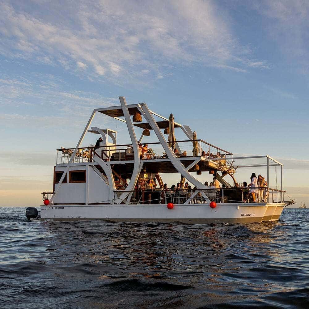 Two-deck catamaran under way on open water, guests along the lower deck