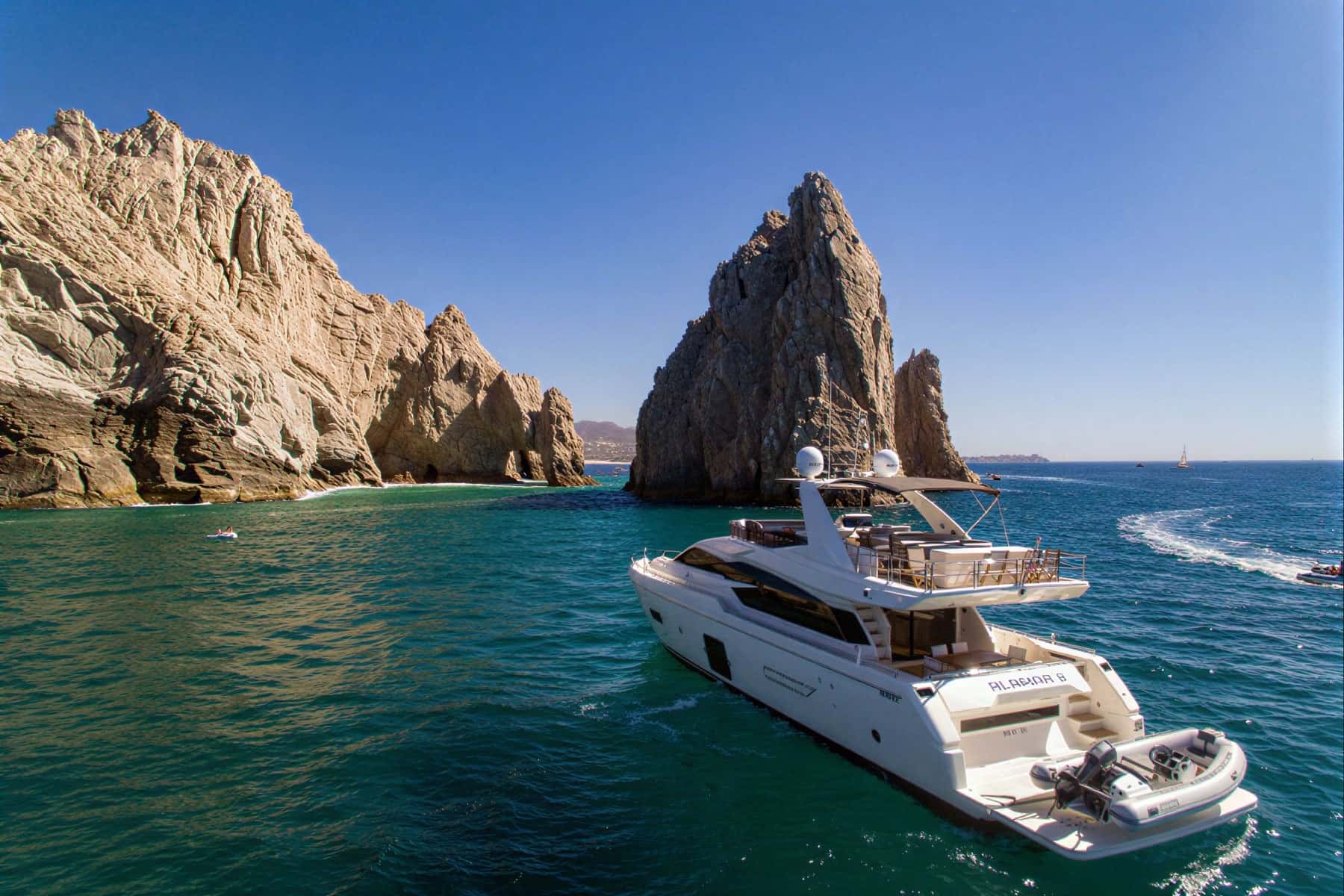 The yacht at anchor off rock formations, a tender on the stern