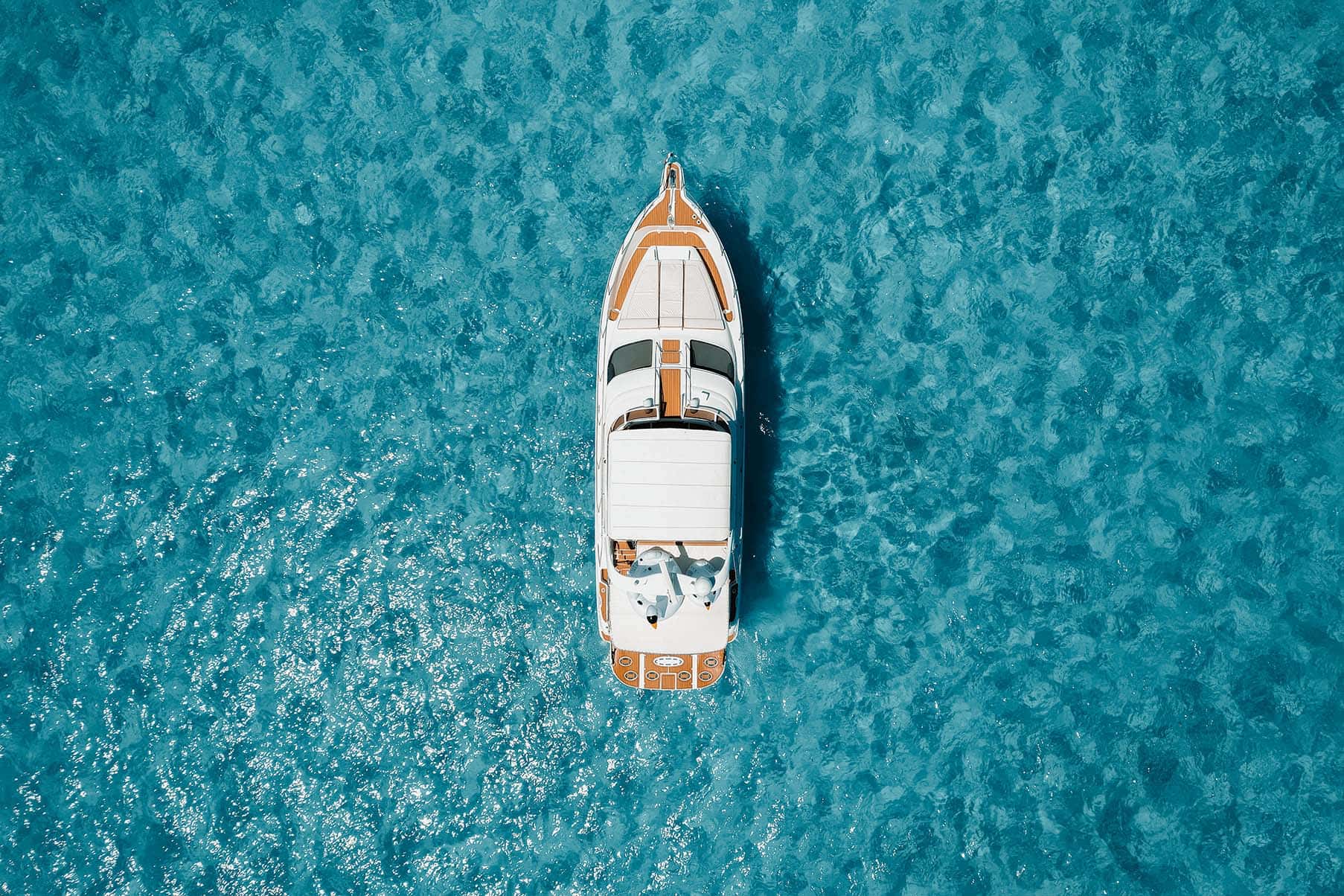 Aerial view straight down on the whole boat over a pale sand bottom