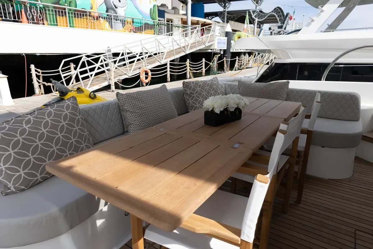 Flybridge dining table in teak with cushioned bench seating under the hardtop
