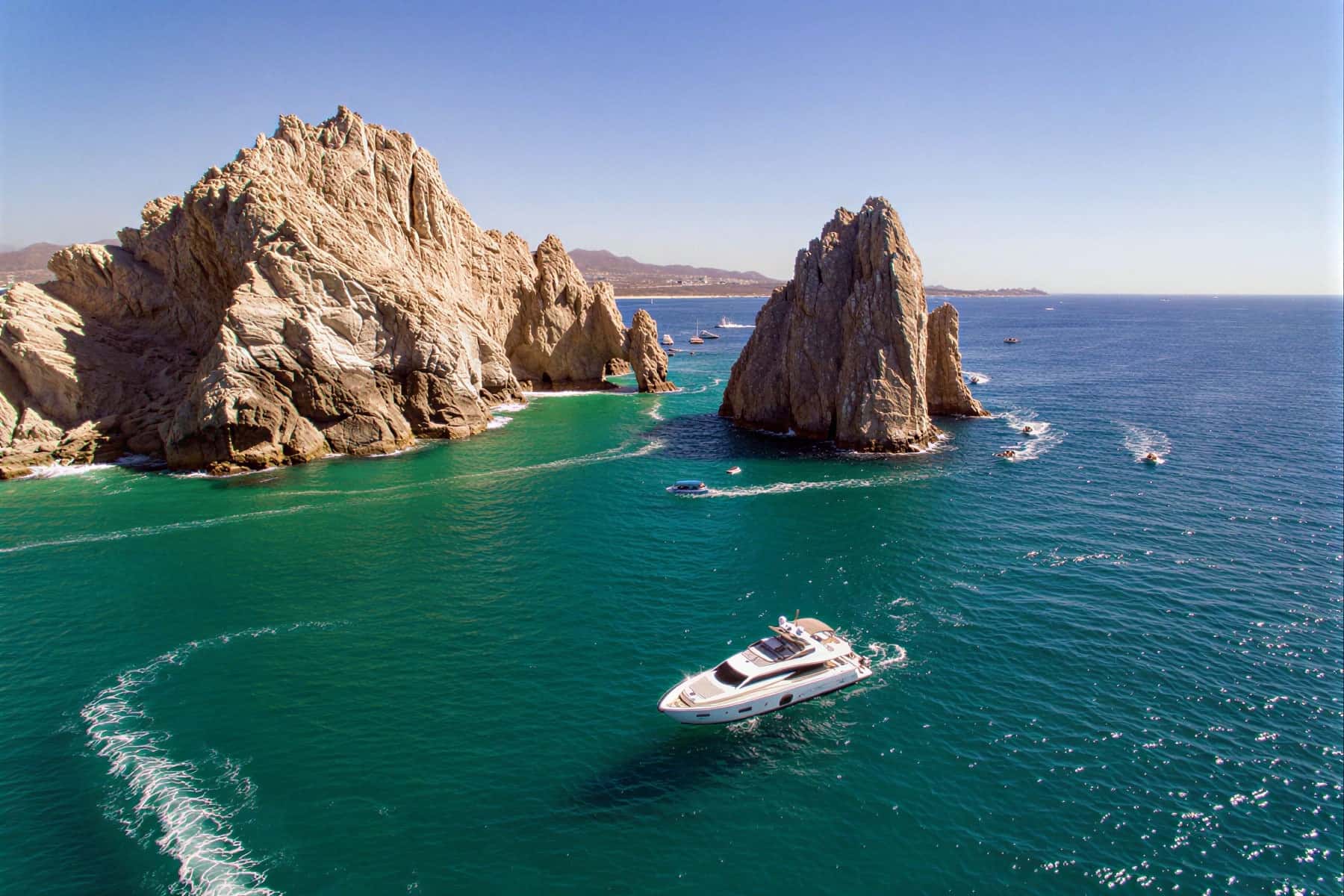 Aerial view of the yacht at sea near rock formations and small boats