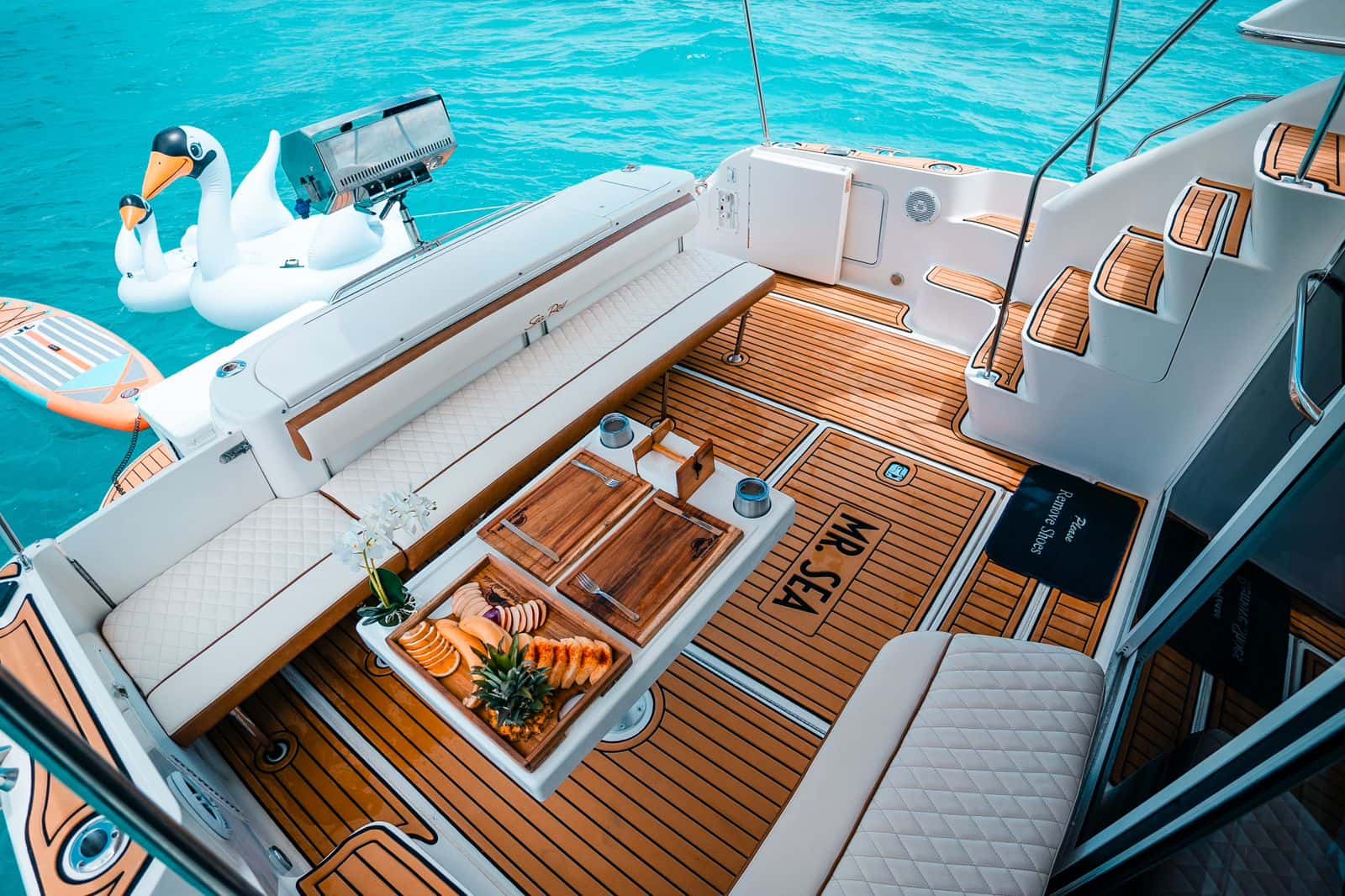 Tray of sliced fruit and pineapple with wooden boards and cutlery on the aft deck table of Mr Sea