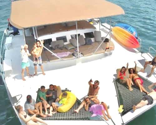 The trimaran from above: guests on the two bow trampolines and bean bags, the shaded lounge deck behind
