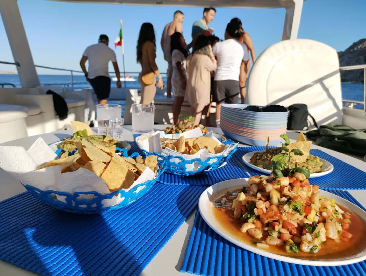 Ceviche, guacamole and chips on the upper deck table with guests behind