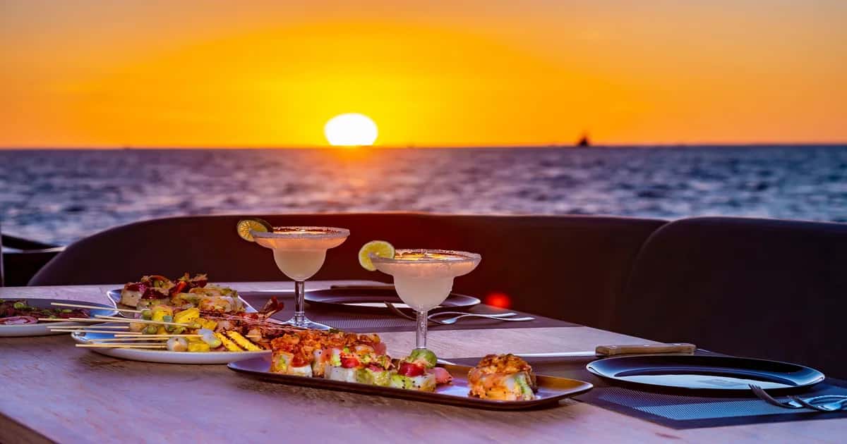 Two margaritas on the table at sunset with the sun on the horizon