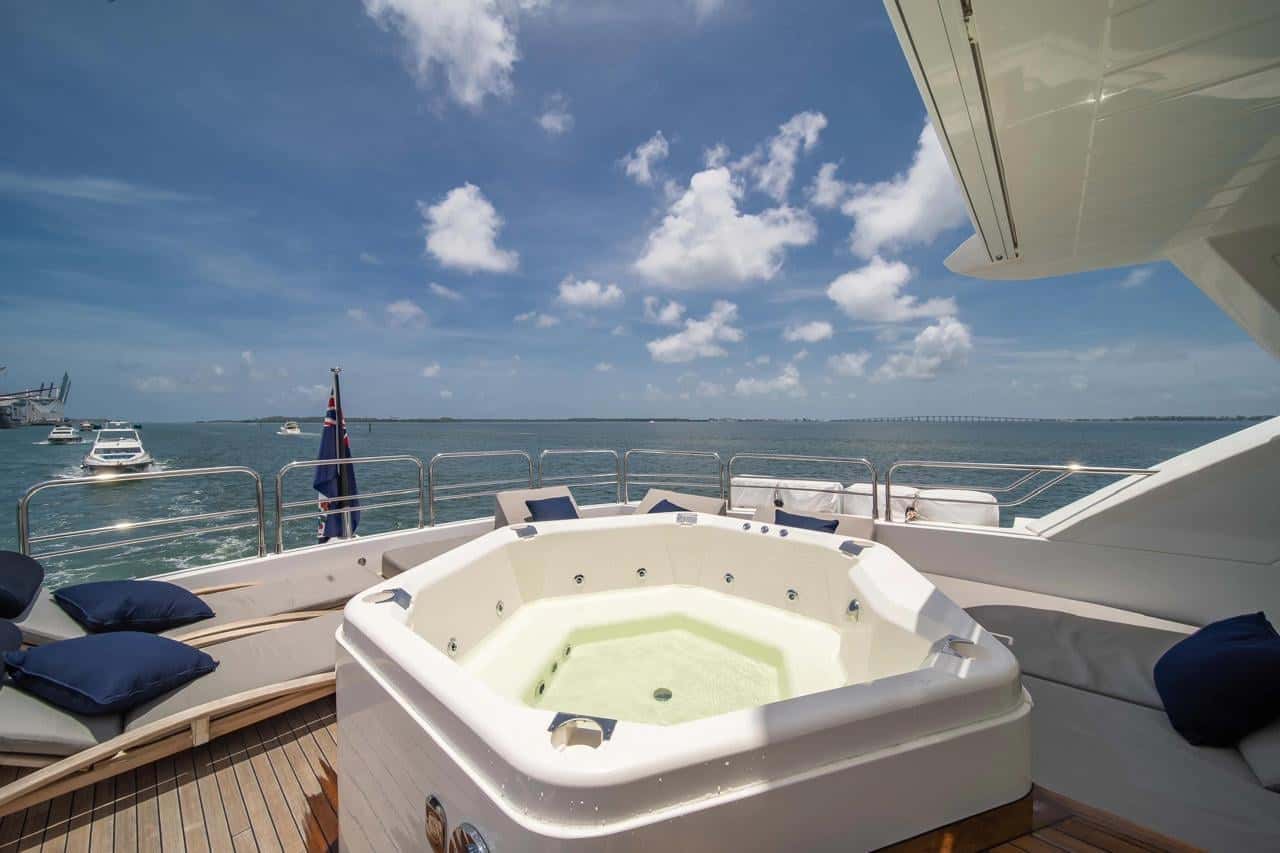 Hot tub on the flybridge with navy cushions on the sun pads and open sea beyond