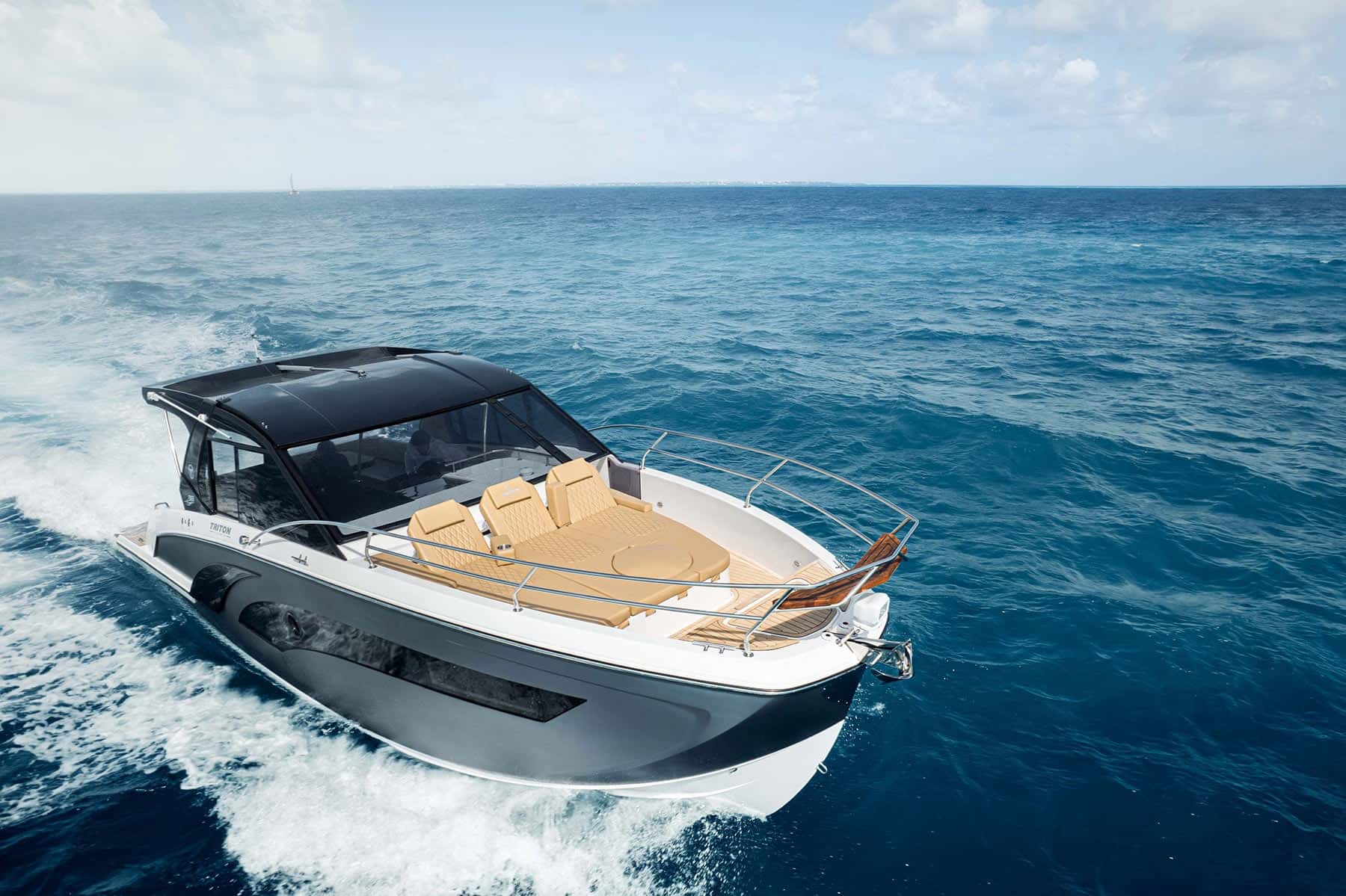 Grey and white hardtop day boat under way on open blue water, three tan sun loungers on the bow