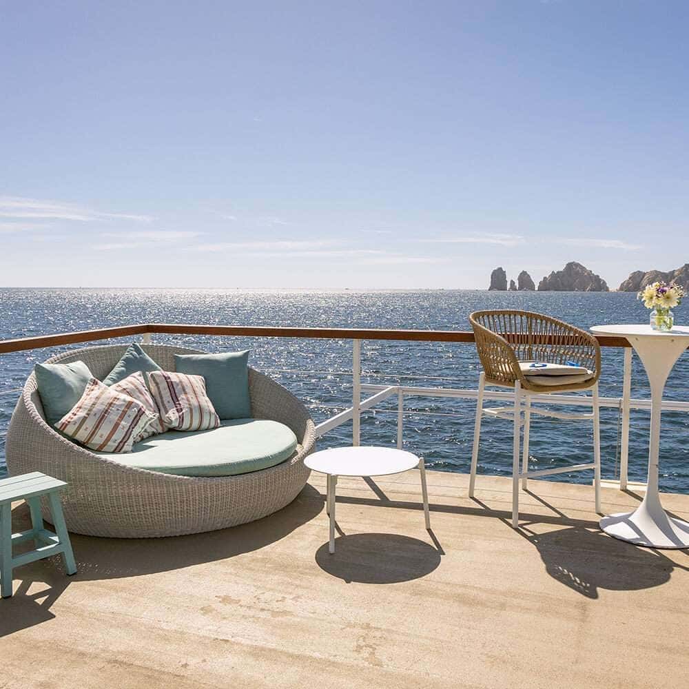 Round wicker daybed and bar stools at the upper deck rail, the Arch rocks on the horizon