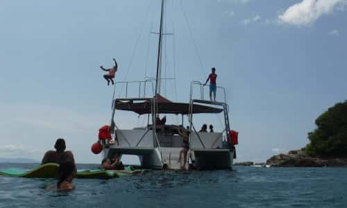 A guest jumping from the high platform over the stern while others swim and float alongside