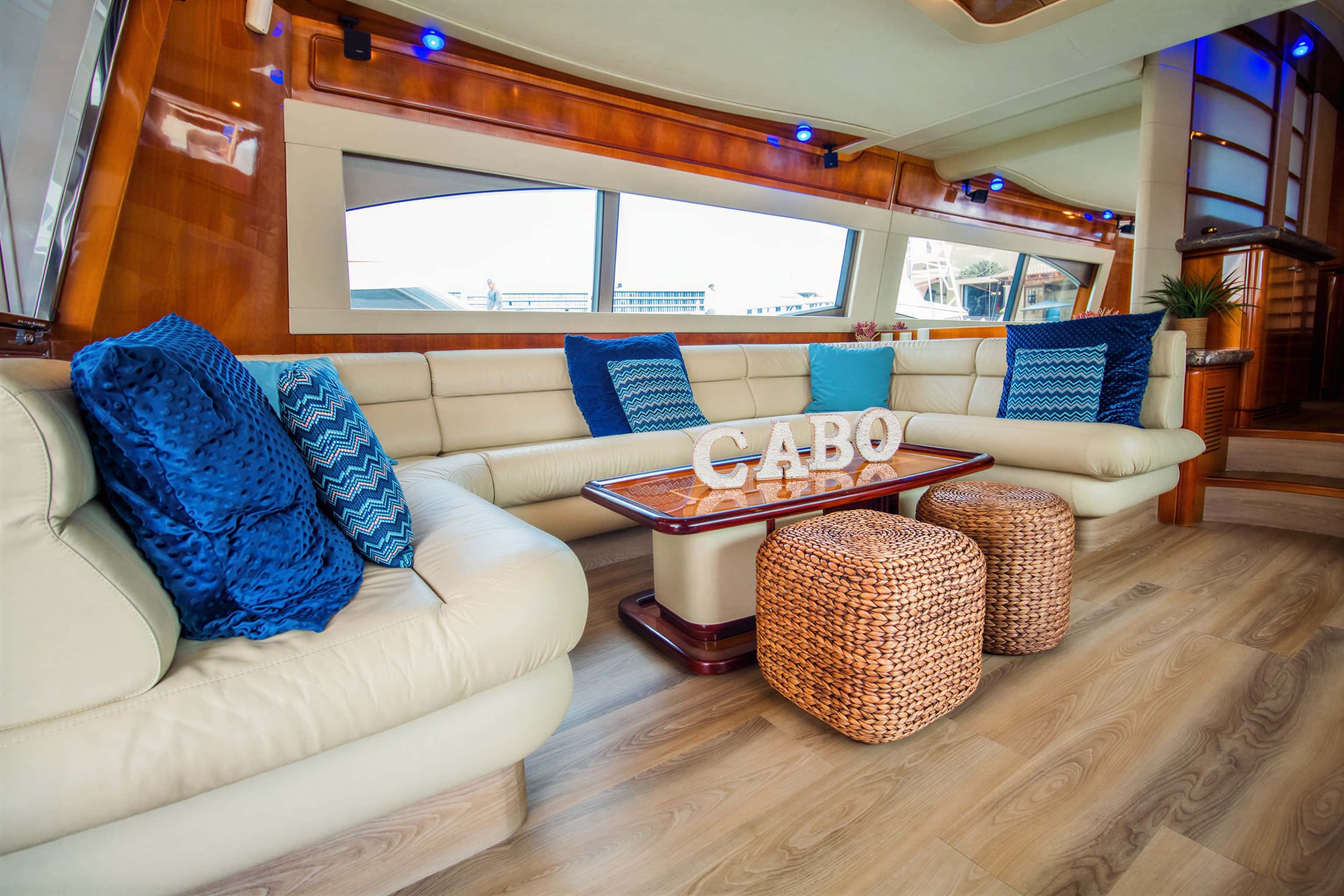 Saloon with a cream leather U-shaped sofa, wooden coffee table, woven poufs and blue cushions