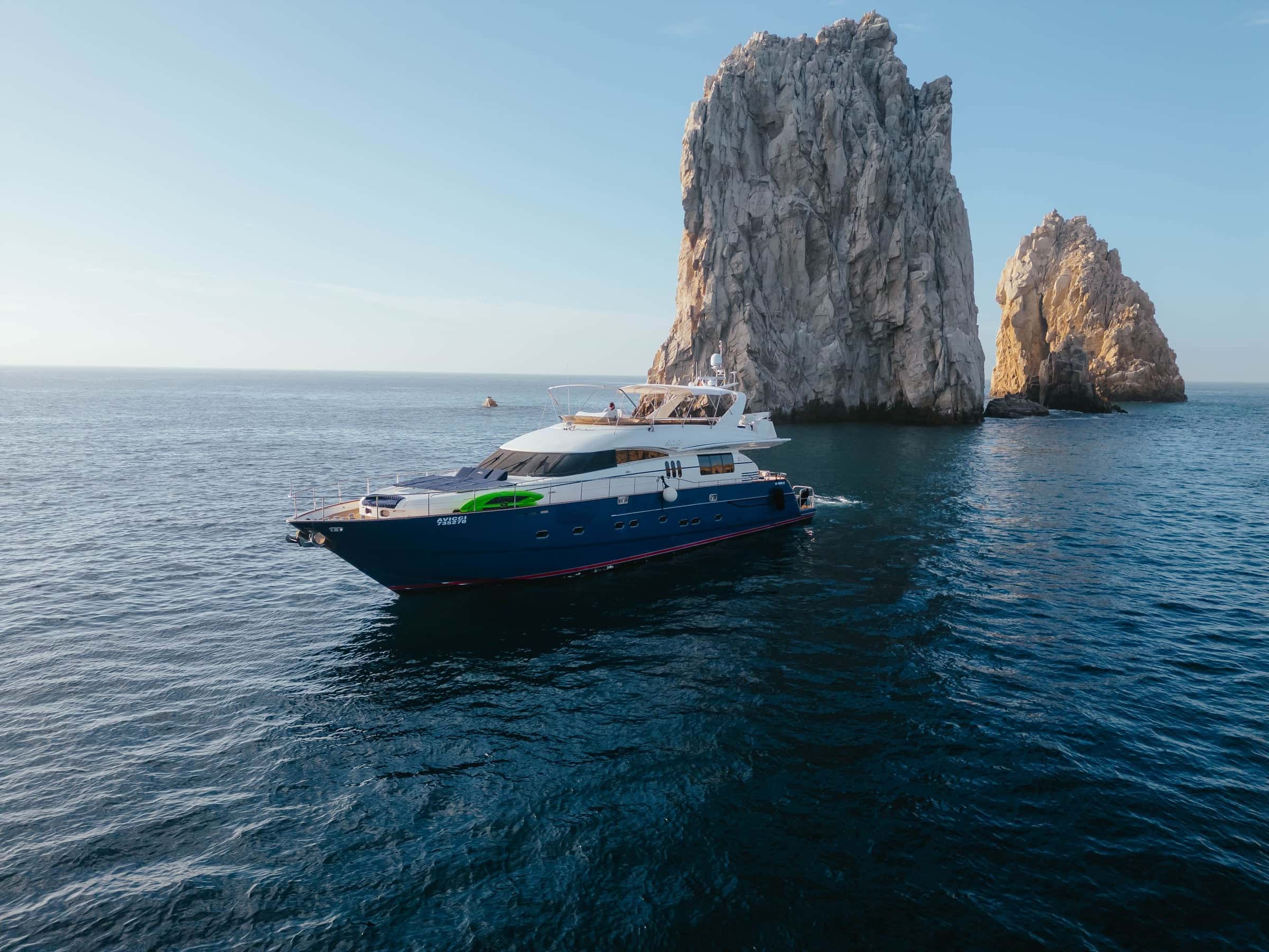 Avicci, a blue-hulled motor yacht, at anchor below the tall rocks of Land's End, Cabo San Lucas