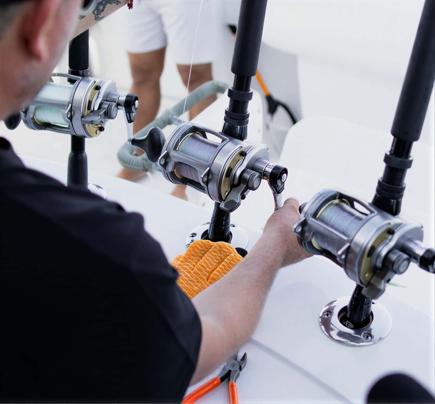 Crew member setting up three big-game reels in the rod holders