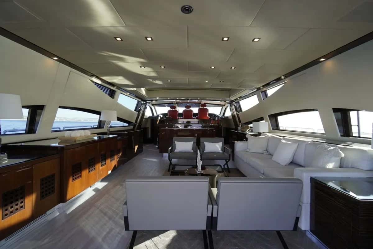 Saloon with a long white sofa, grey armchairs, wood cabinetry and the helm seats at the far end