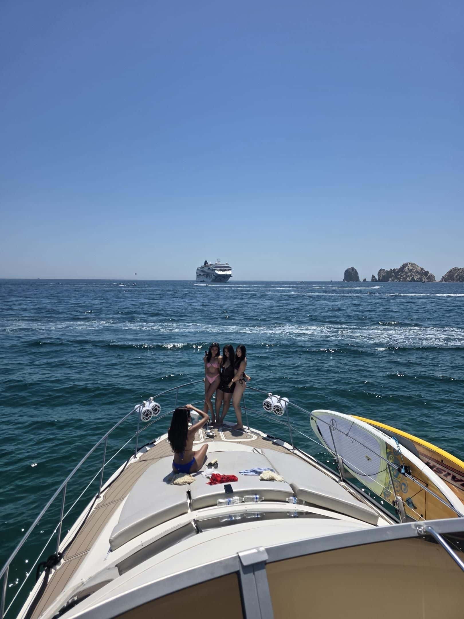 Guests on the bow sun pad as the yacht heads out to sea, a paddleboard stowed on the rail