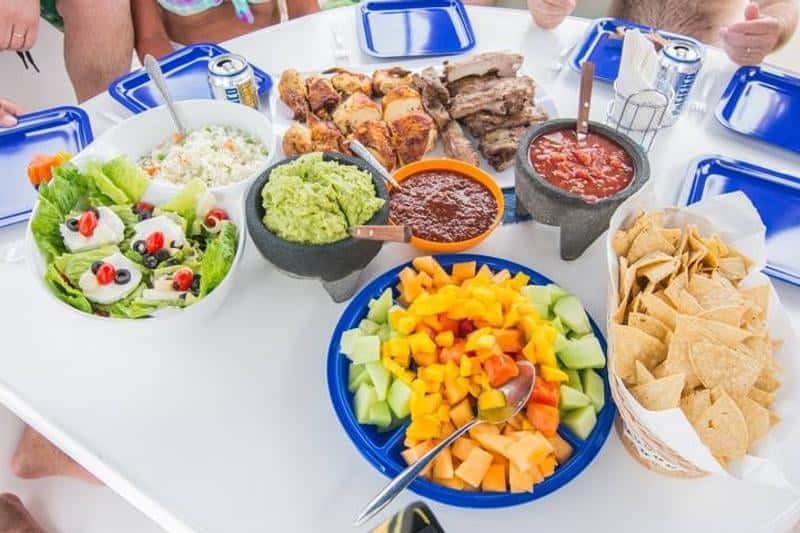 Lunch on the deck table: guacamole, salsa, chips, fruit, salad and grilled meat