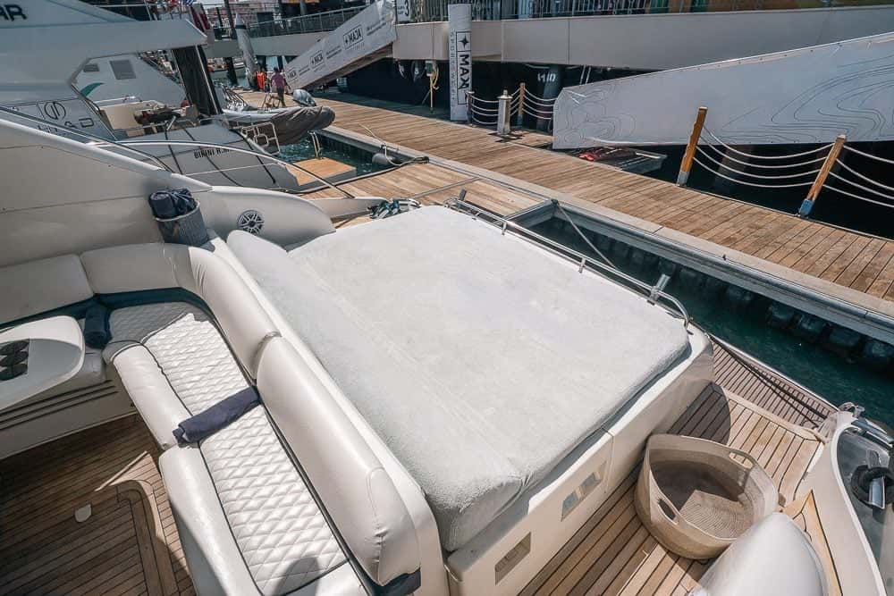 The aft sun pad and a quilted bench seat on the teak deck, moored in the marina