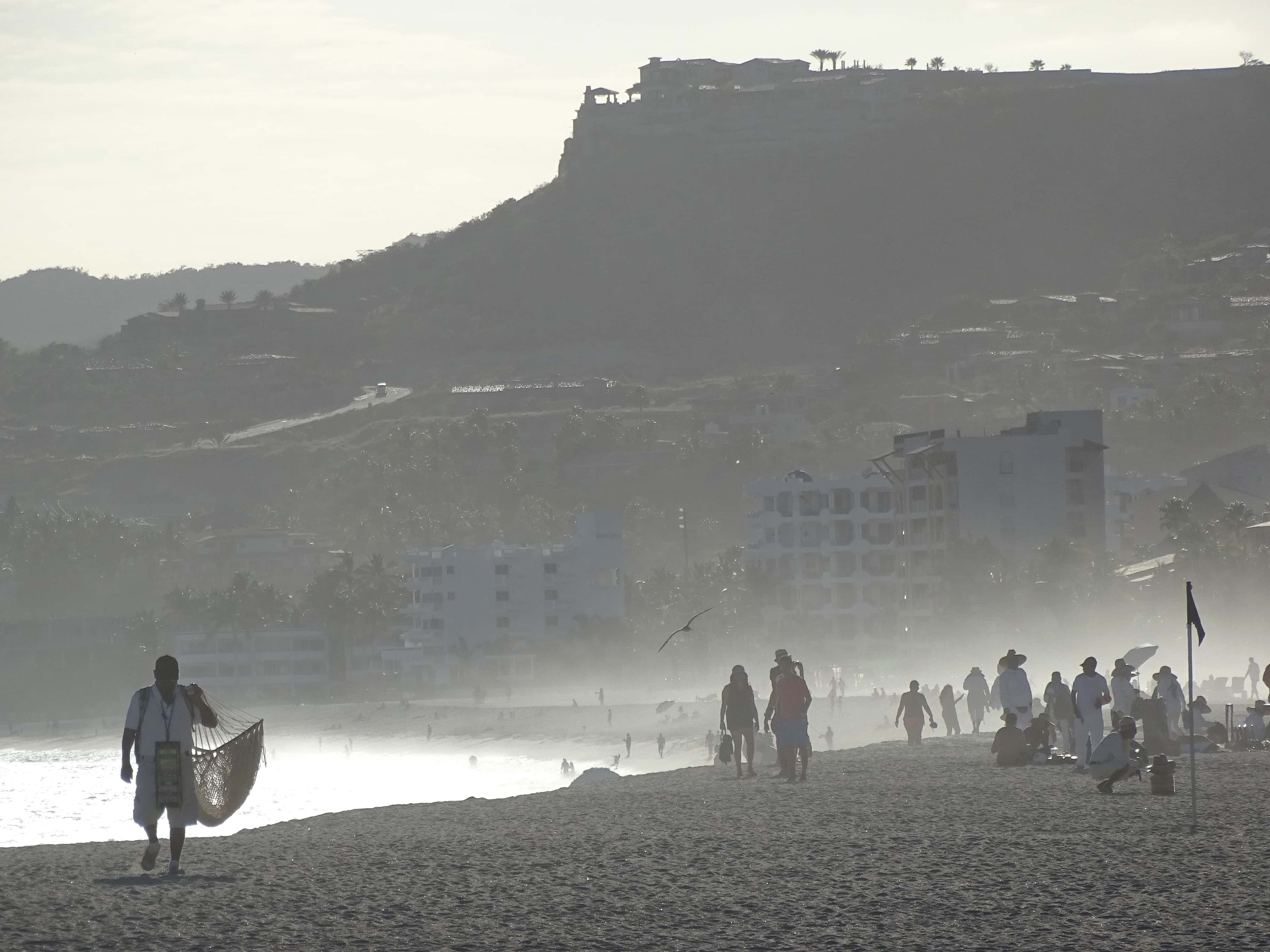 San José del Cabo: walkers on the beach in the afternoon haze