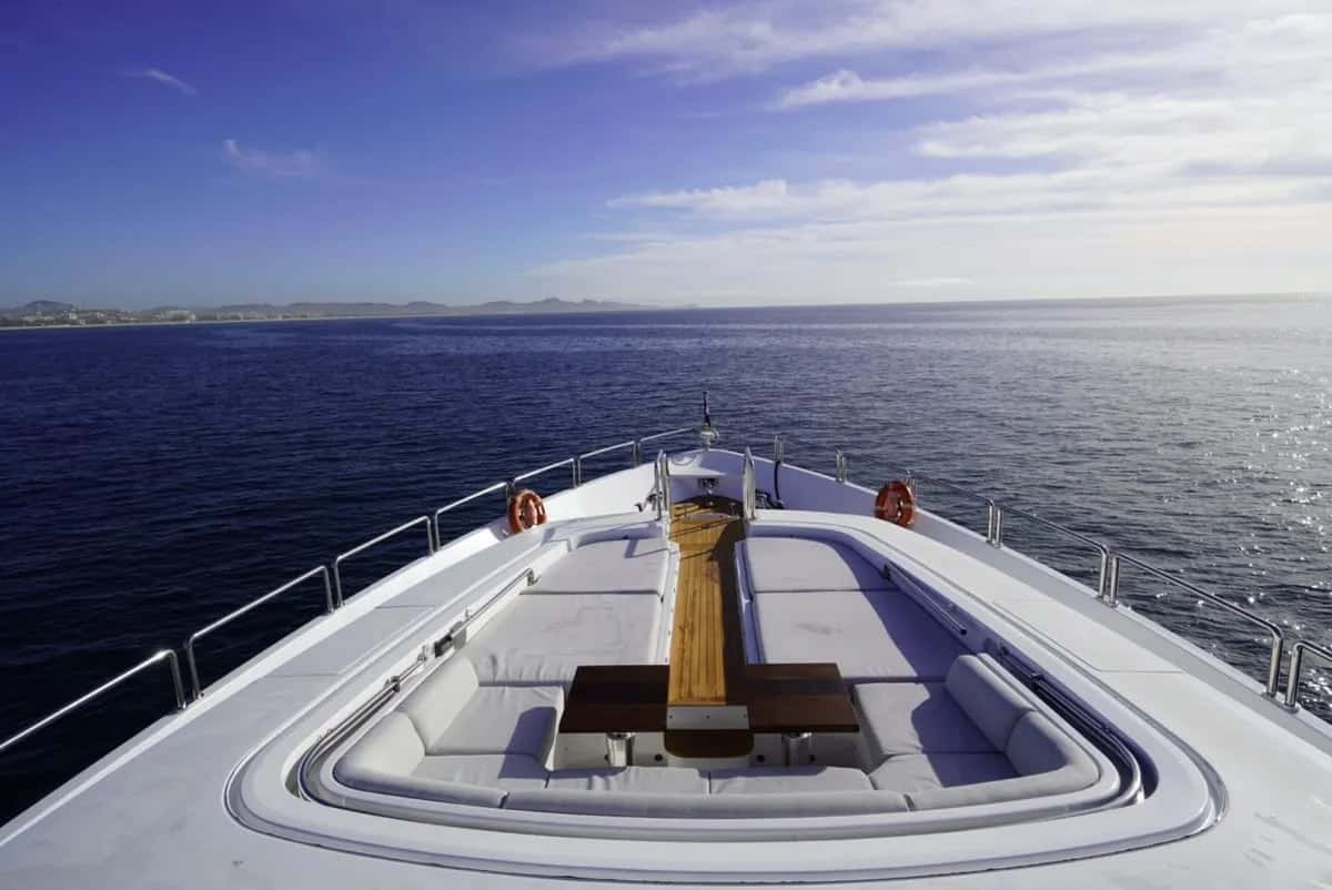 Foredeck sunbathing area with cushioned seating, two lifebuoys and a teak walkway