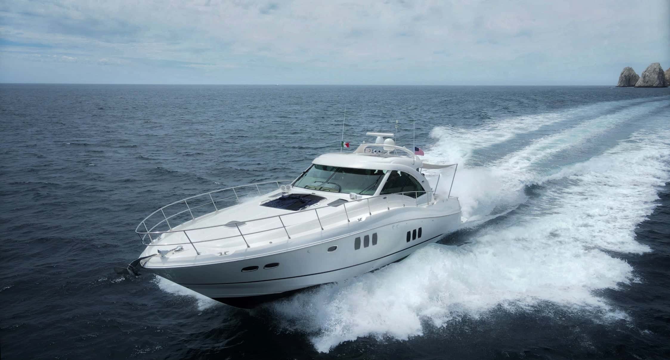 Side view of the white Sea Ray cruising fast on grey-blue water, the wake curling behind