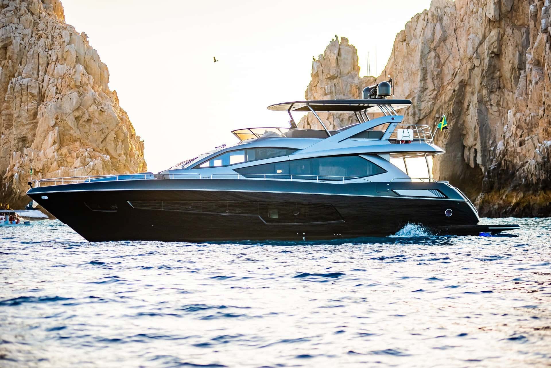 Black motor yacht in profile beside the rock cliffs at Land's End