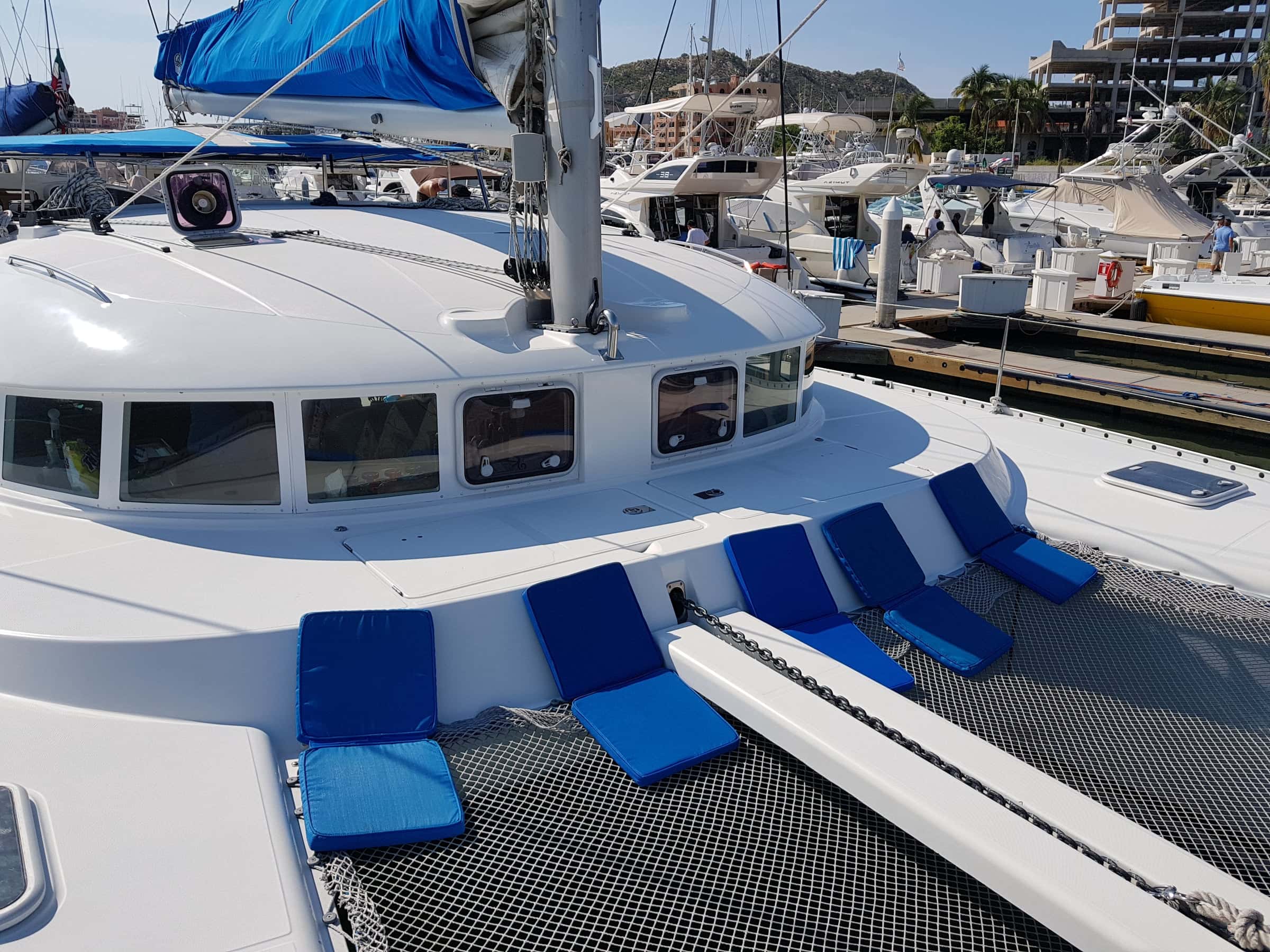 Foredeck with blue sun cushions along the coachroof windows and the trampoline net below