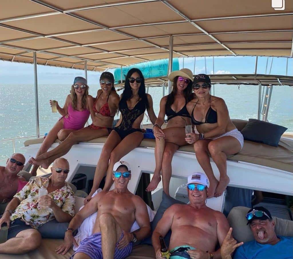 Group of guests with drinks relaxing on cushioned seating under a shade canopy