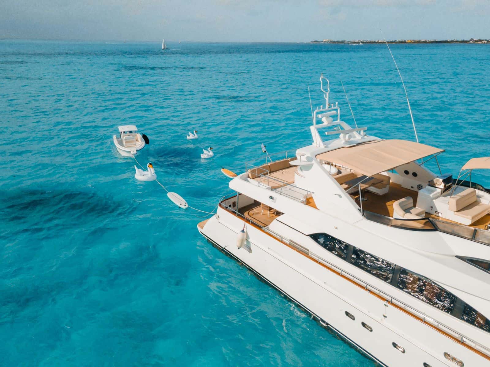 Aerial view of the yacht's stern quarter with white swan floats, paddleboards and a tender towed alongside