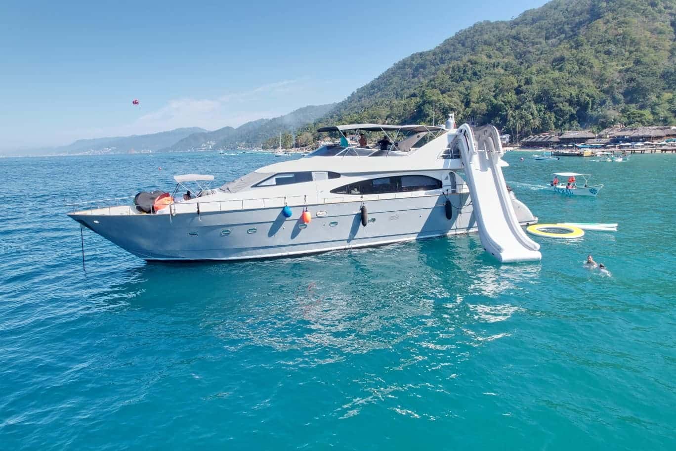 Don Moi seen from the side at anchor with an inflatable slide, floating mat and a swimmer in the water