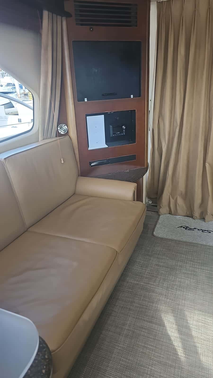 Salon sofa in tan leather beside a wall unit with a TV and a stereo