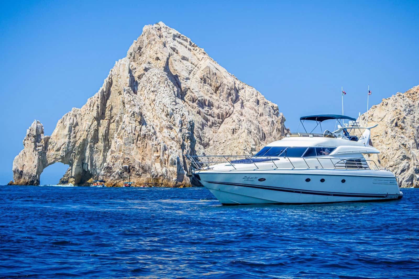 Zinfull motor yacht on blue water in front of the Cabo San Lucas arch rock formation