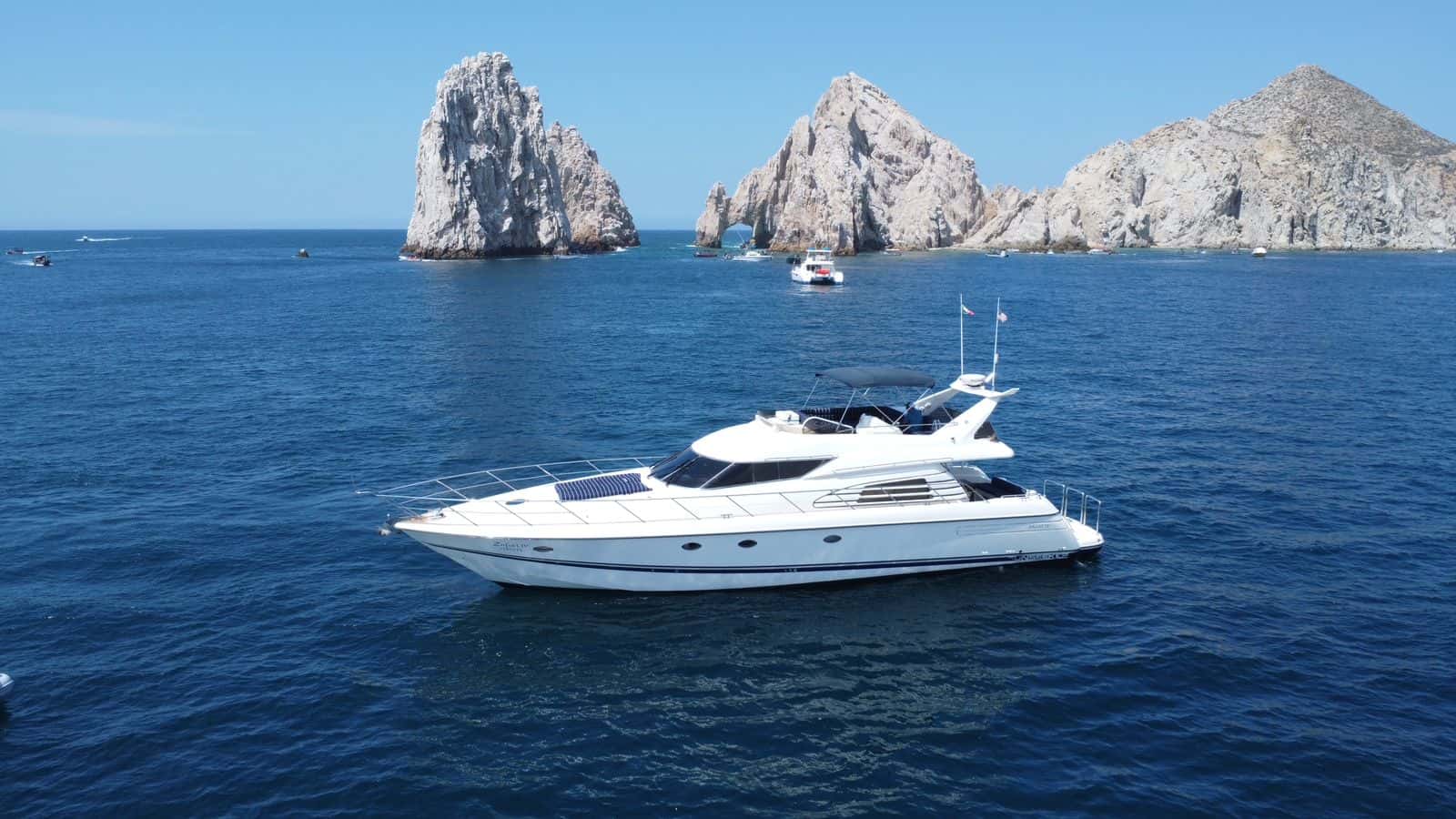 Aerial side view of Zinfull cruising off the Cabo rocks with the flybridge Bimini up
