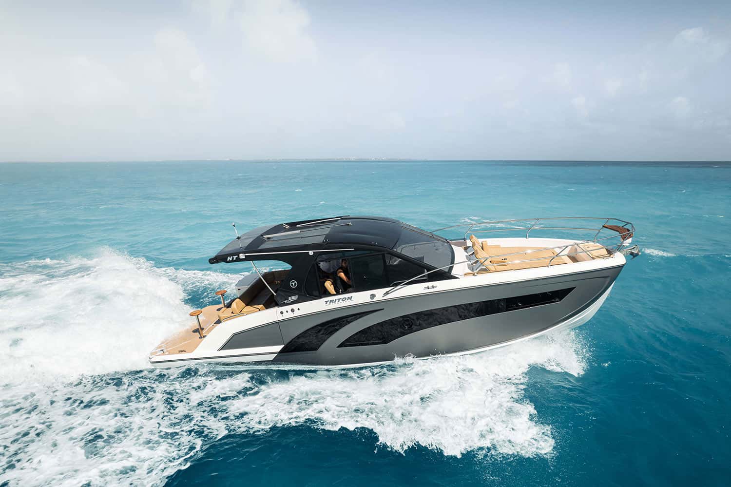 Gray and white motor yacht with a dark hardtop speeding across turquoise water, seen from the side