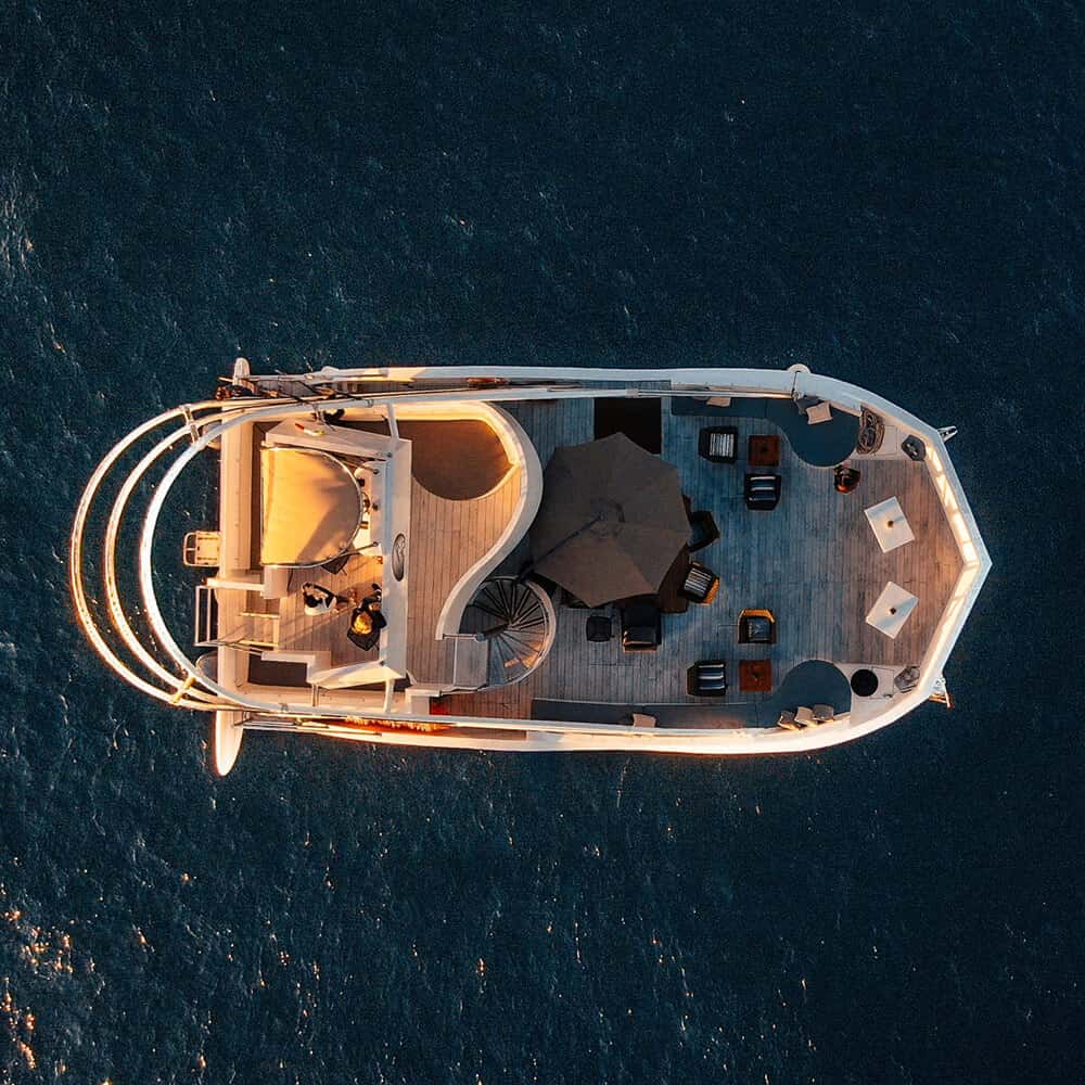 Pelican X seen from directly above, with seating and an umbrella on deck, on dark water