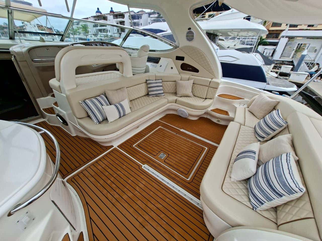 Cockpit with quilted cream sofas, striped cushions and teak-style decking under the hardtop