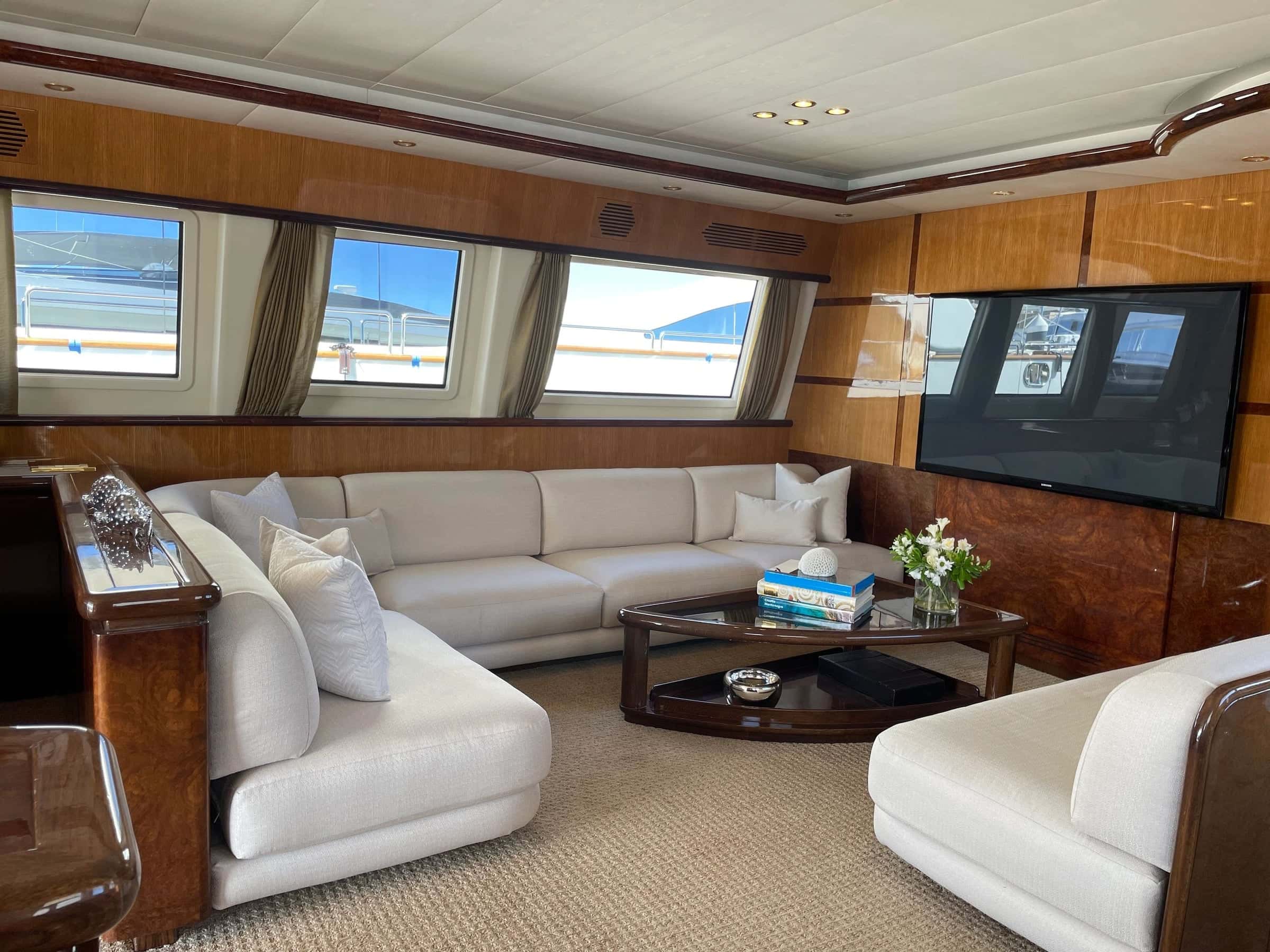 Main saloon with white sectional sofas, burl wood cabinets and wide windows
